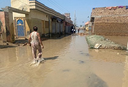 Ein Mann läuft eine überflutete Straße entlang.