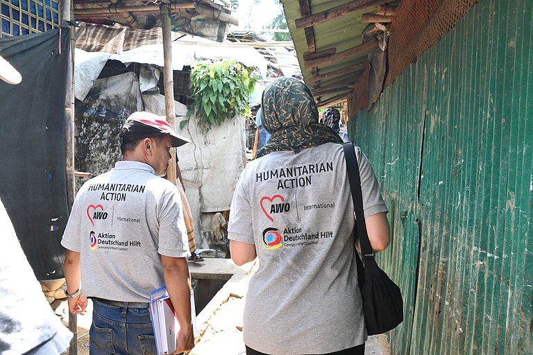 Zwei Menschen laufen, man sieht sie von Hinten. Sie tragen t-Shirts mit dem Logo von AWO International.