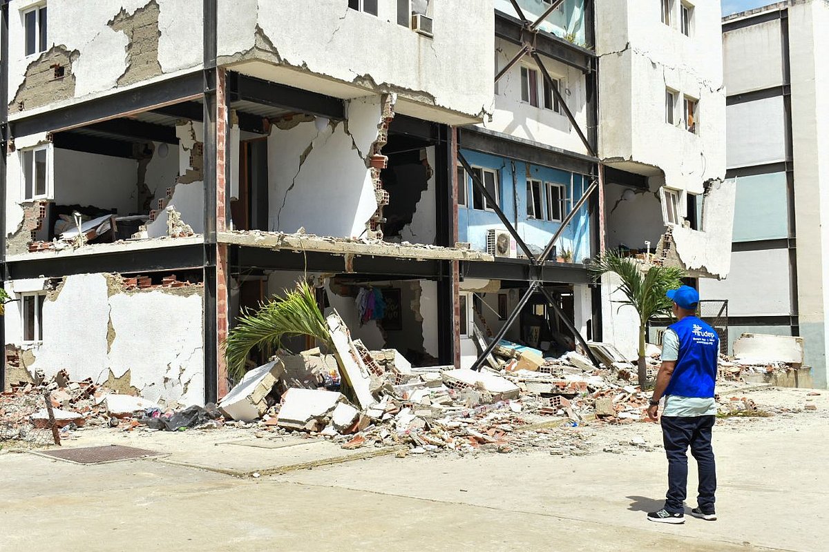 Ein Mitarbeiter von FUDEO steht vor einem zerstörten Haus