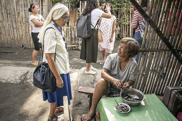 Schwester Ritaflor Servidad von OND HESED (links) spricht mit Esmeralda Magsanay (rechts), einer Anwohnerin von San Juan, General Santos City, die Fisch zum Essen vorbereitet. (Foto: AWO International)