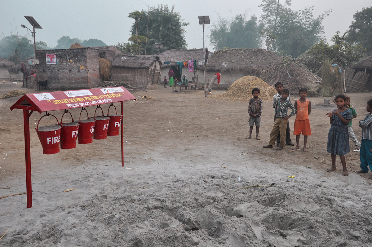 Children stand in front of extinguishing stations with sand