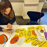 A woman writes on colorful index cards.