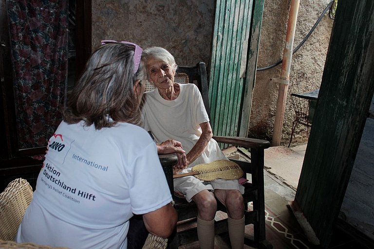 Eine Mitarbeiterin des CCRD-Cubas unterhält sich mit einer Seniorin und hält ihre Hand