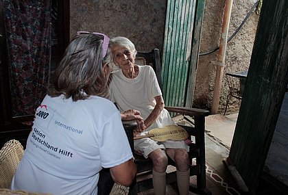 Eine Mitarbeiterin des CCRD-Cubas unterhält sich mit einer Seniorin und hält ihre Hand