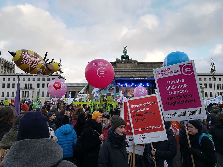 Menschen mit dem Demo-Plakaten stehen vor dem Brandenburger Tor 