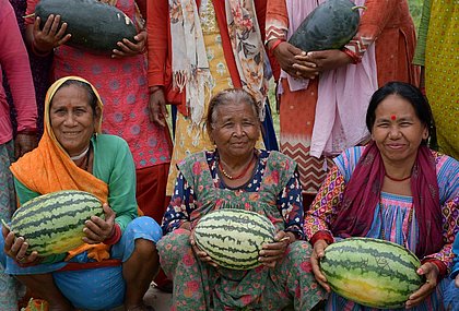 Drei Frauen halten eine Wassermelone.
