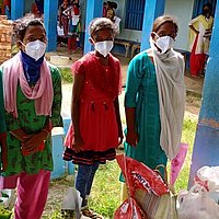 Eine Gruppe junger Frauen erhält Nothilfepakete mit Hygienematerialien