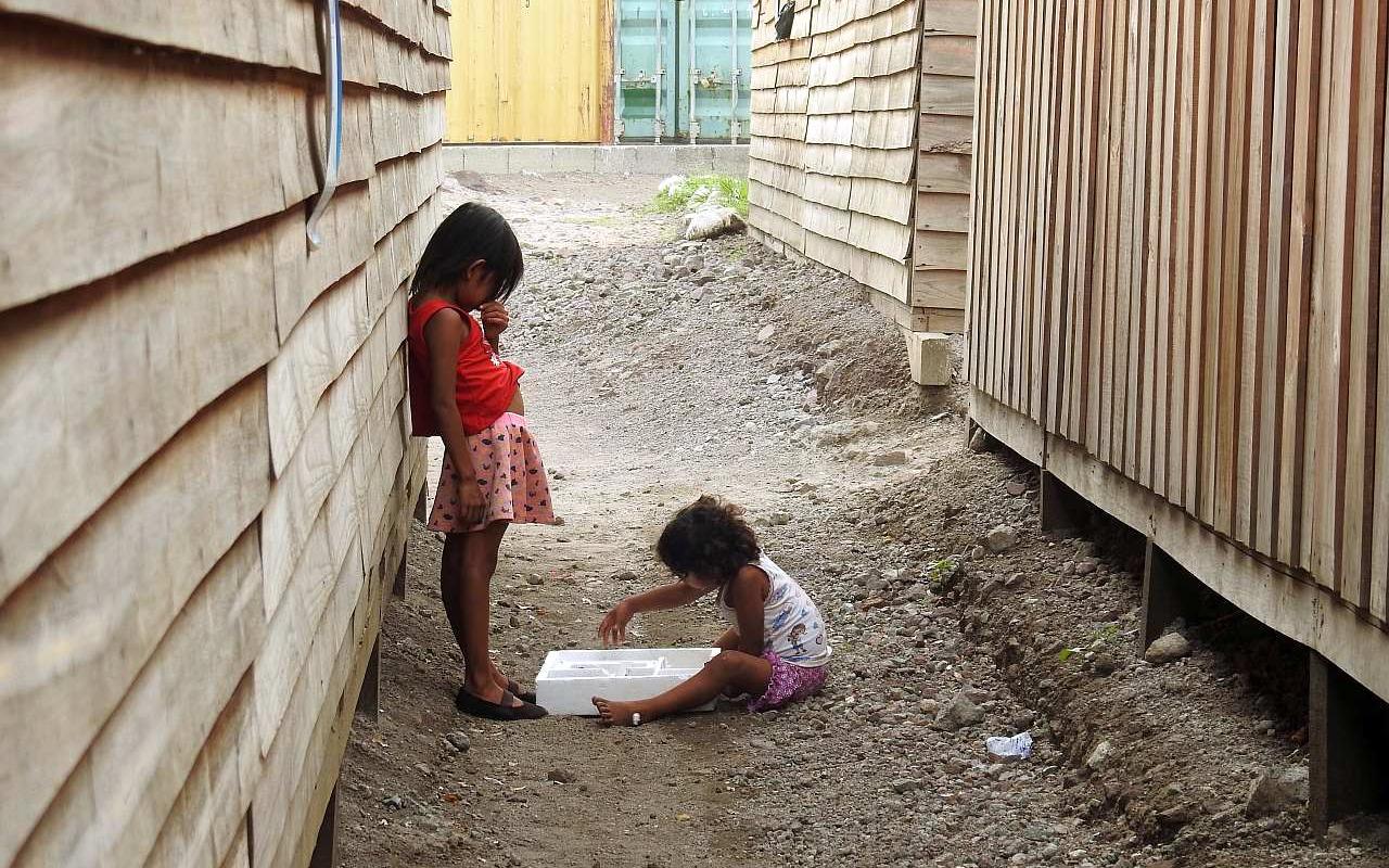 Children playing in front of the wooden houses (ATUS) where 1000 families are expected to spend 18 months while their permanent homes are built (Photo: AWO International)