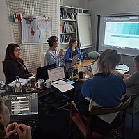 A group of people are sitting at a table in a seminar room.