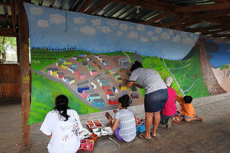 Frauen und Kinder verarbeiten ihre Erfahrungen in einem Leintuch-Gemälde (Foto: AWO International)