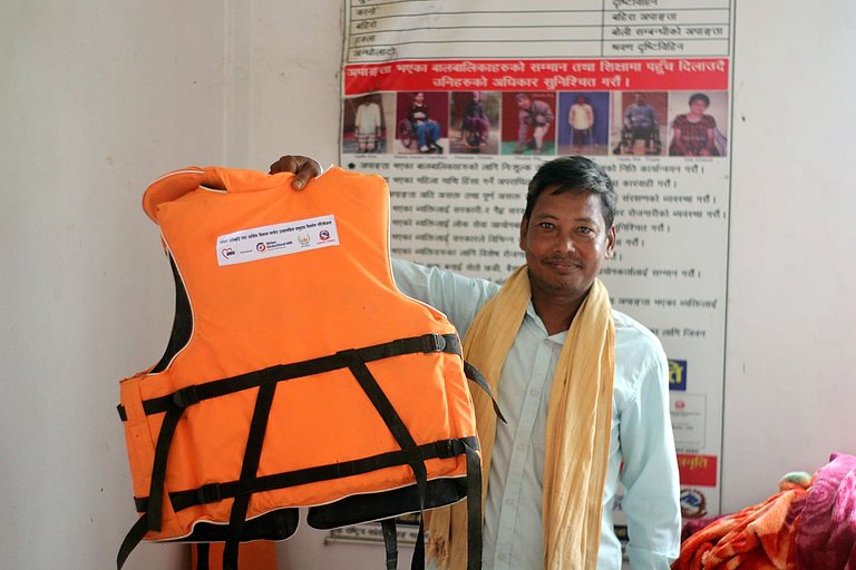 A man holds up a life jacket.