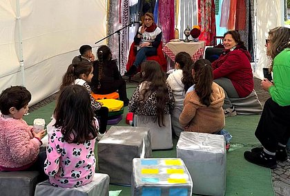 Eine Frau liest ein Buch und Kinder hören zu.