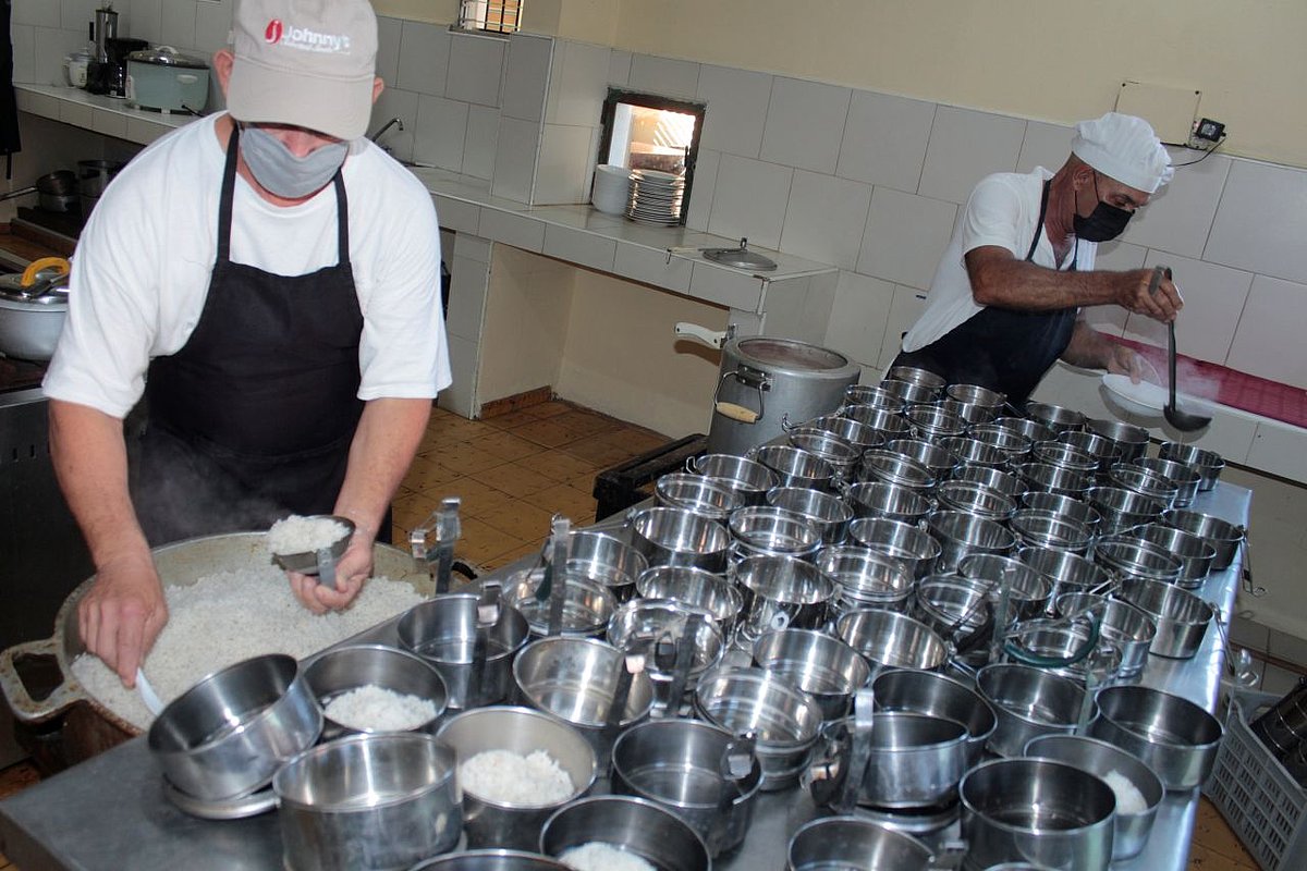 Zwei Mitarbeitende portionieren Mahlzeiten in Dosen. 